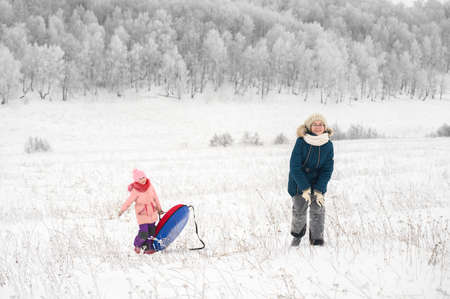 Sisters is riding an inflatable sleigh from the hill. Outdoor activity recreation. Open-air living and Scandinavian concept: Fruitsliv.の写真素材