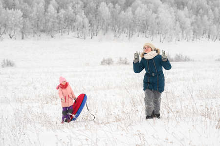 Sisters is riding an inflatable sleigh from the hill. Outdoor activity recreation. Open-air living and Scandinavian concept: Fruitsliv.の写真素材