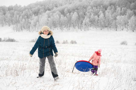 Sisters is riding an inflatable sleigh from the hill. Outdoor activity recreation. Open-air living and Scandinavian concept: Fruitsliv.の写真素材