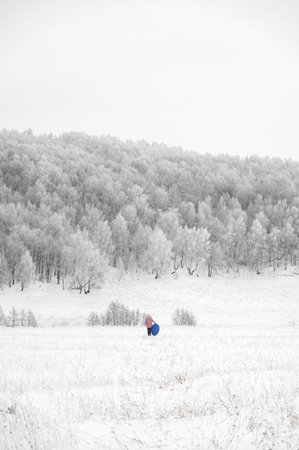 Woman is riding an inflatable sleigh from the hill. Outdoor activity recreation. Open-air living and Scandinavian concept: Fruitsliv. Tiny humans big worldの写真素材