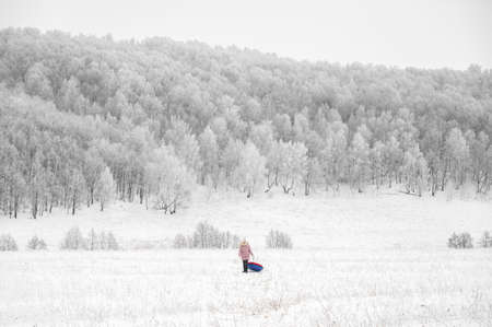 Woman is riding an inflatable sleigh from the hill. Outdoor activity recreation. Open-air living and Scandinavian concept: Fruitsliv. Tiny humans big worldの写真素材