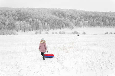 Woman is riding an inflatable sleigh from the hill. Outdoor activity recreation. Open-air living and...