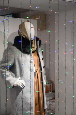 Store showcase with a mannequin in winter clothes. Holiday sale concept. Winter Christmas decoration, nighttime.の写真素材