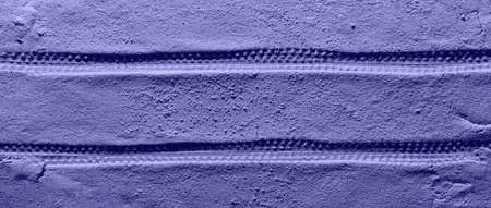 Tire pattern on the reddish-orange sandy surface with copy space. Imitation of the traces of the rover on the planet Mars. Top view, banner. Toned in trendy Color Of The Year 2022 - Very Peri.の写真素材