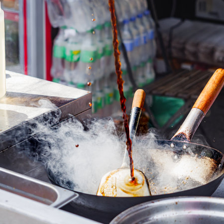 Chef Stir-Frying Sweet Chili Chicken with Vegetables in a Wok: Street Food Festival Sceneの写真素材