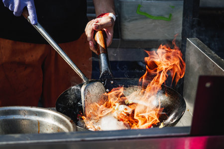 Chef Stir-Frying Seafood and Vegetables in a Wok at a Street Food Festival.の写真素材