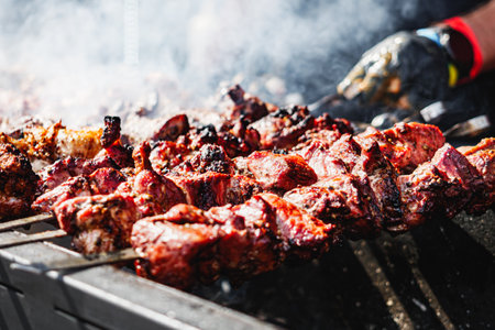 Man Grilling Steaks and Ribs: Hands at Work at a Vibrant BBQ Festival.の写真素材