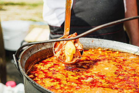 Traditional Hungarian Goulash: Hearty Soup with Meat and Vegetables at a Vibrant Street Food Festival.の写真素材