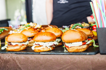 Handheld Gourmet Burger: Juicy Street Food Festival Delight with Bacon, Cheese, and Vegetables.の写真素材