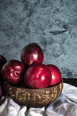 Juicy Summer Plums: Fresh Red and Black Plums on a Rustic Wooden Background.の写真素材