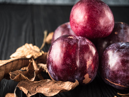 Juicy Summer Plums: Fresh Red and Black Plums on a Rustic Wooden Background.の写真素材