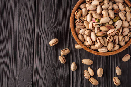 Cracked Pistachios: Healthy, Crunchy Nuts on Wooden and Black Backgrounds.の写真素材