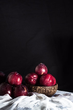 Juicy Summer Plums: Fresh Red and Black Plums on a Rustic Wooden Background.の写真素材