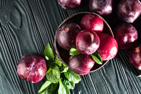Juicy Summer Plums: Fresh Red and Black Plums on a Rustic Wooden Background.の写真素材