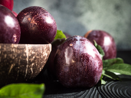 Juicy Summer Plums: Fresh Red and Black Plums on a Rustic Wooden Background.の写真素材