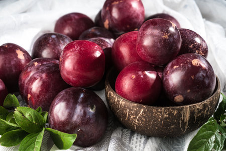 Juicy Summer Plums: Fresh Red and Black Plums on a Rustic Wooden Background.の写真素材