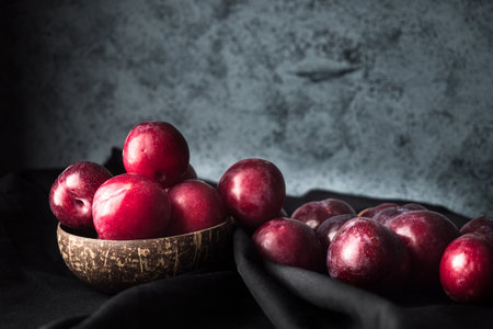 Juicy Summer Plums: Fresh Red and Black Plums on a Rustic Wooden Background.の写真素材