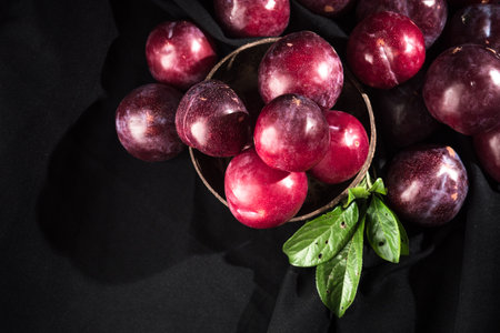 Juicy Summer Plums: Fresh Red and Black Plums on a Rustic Wooden Background.の写真素材