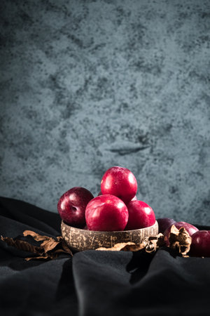 Juicy Summer Plums: Fresh Red and Black Plums on a Rustic Wooden Background.の写真素材