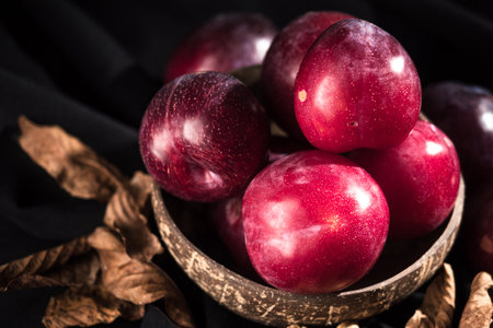 Juicy Summer Plums: Fresh Red and Black Plums on a Rustic Wooden Background.の写真素材