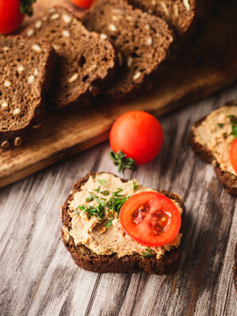 Rustic Pate, man smear on Black Bread with Fresh Herbs and tomatoes