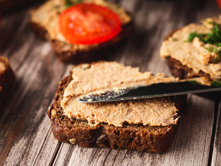 Rustic Pate, man smear on Black Bread with Fresh Herbs and tomatoesの写真素材
