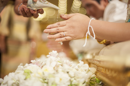 hands pouring blessing water into bride's bands, Thai wedding ceremonyの写真素材