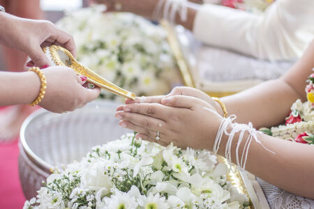 hands pouring blessing water into bride's bands, Thai wedding ceremonyの写真素材