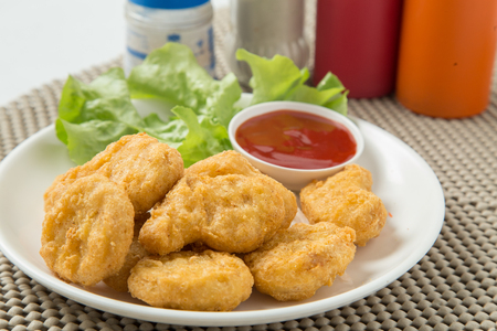 A pile of chicken nuggets on white plate with sauceの写真素材
