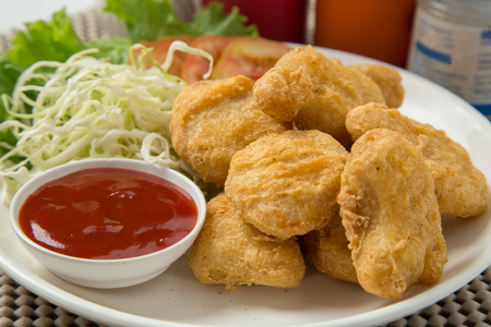 A pile of chicken nuggets on white plate with sauceの写真素材