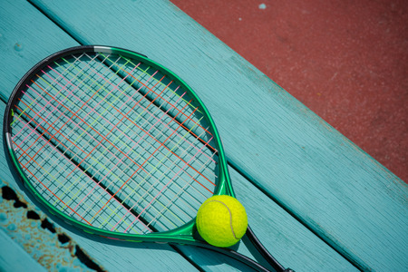 A tennis racket with tennis ball on green wood textureの写真素材