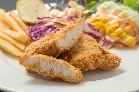 Fish dish - fried fish fillet with vegetables on black backgroundの写真素材