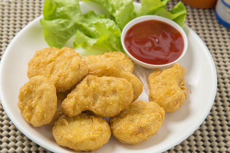 A pile of chicken nuggets on white plate with sauceの写真素材