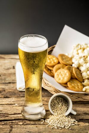 beer in a glass and popcorn on dark backgroundの写真素材