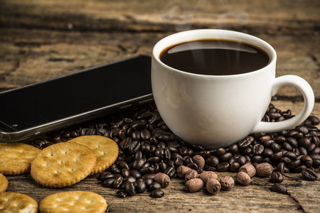 Cup of hot coffee on a old wooden table with coffee bean and  biscuitsの写真素材
