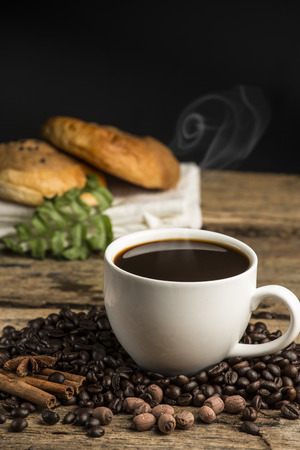 Cup of hot coffee on a old wooden table with coffee bean and  biscuitsの写真素材