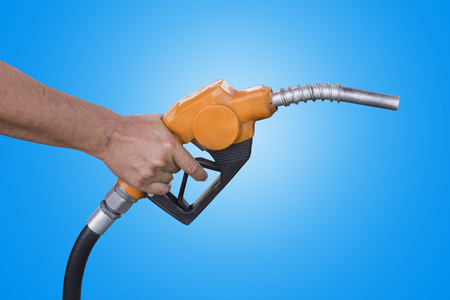 Holding a fuel nozzle against blue backgroundの写真素材