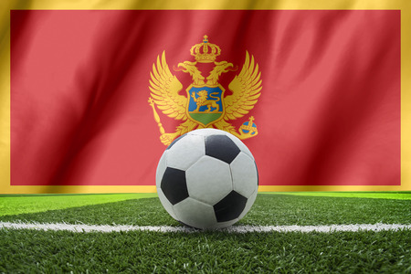 Soccer ball and national flag of Montenegro lies on the green grassの写真素材
