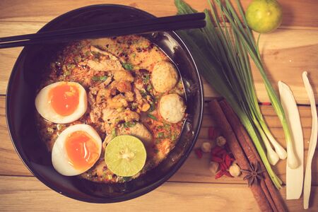 bowl of noodles with vegetables and soft boiled egg on wooden table. delicious noodle. Instant noodle. hot noodle.Homemade Quick Ramen Noodles with egg.vintage colorの写真素材