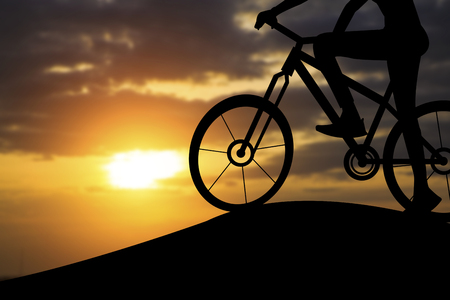 Silhouette of a woman on muontain bike, sunset.の写真素材