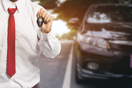 Male holding car keys with car on backgroundの写真素材