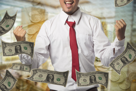 A young successful man, male executive businessman arms raised celebrating cheering shouting in front of officeの写真素材