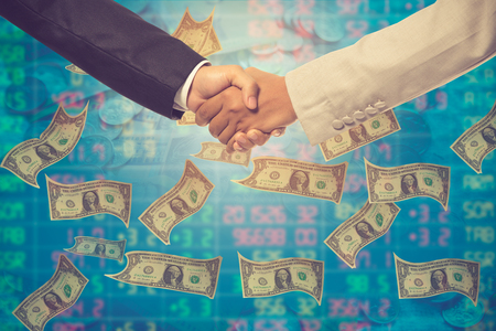Business handshake. Business handshake and business people concept. Two men shaking hands over money background.Vintage colorの写真素材