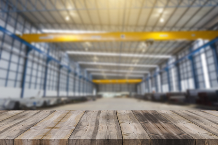 Wood table top on blur factory hall (or garage) background - can be used for display or montage your productsの写真素材