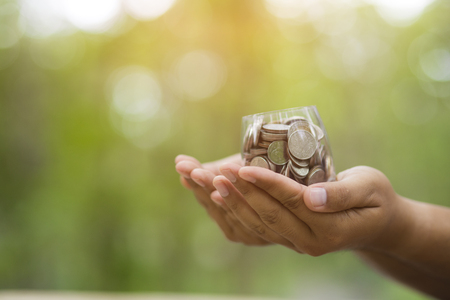 Hand with coins on bokeh background .save money conceptの写真素材