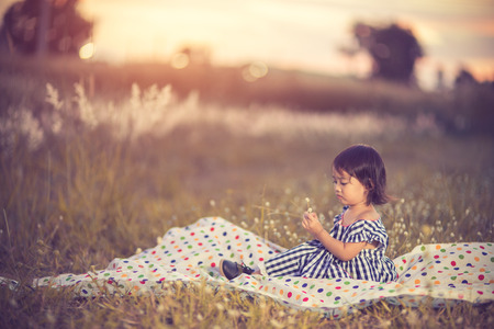Blurred of Happy cute kid in a field playing with natural spikes at summer sunset. Soft colors edition.Soft focus.Vintage colorの写真素材