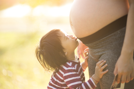 happy family, a pregnant mother and daughter little girl child in the sunlightの写真素材