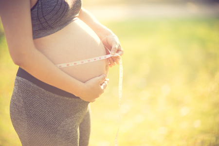 Pregnant woman measuring her belly with tape measure.の写真素材