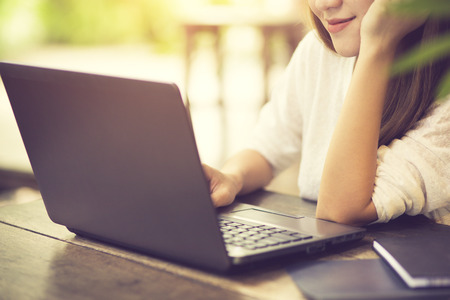 Beautiful Caucasian woman dreaming about something while sitting with portable net-book in modern cafe bar, young charming female freelancer thinking about new ideas during work on laptop computerの写真素材
