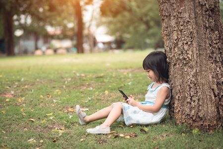 little girl with a mobile phone in the parkの写真素材